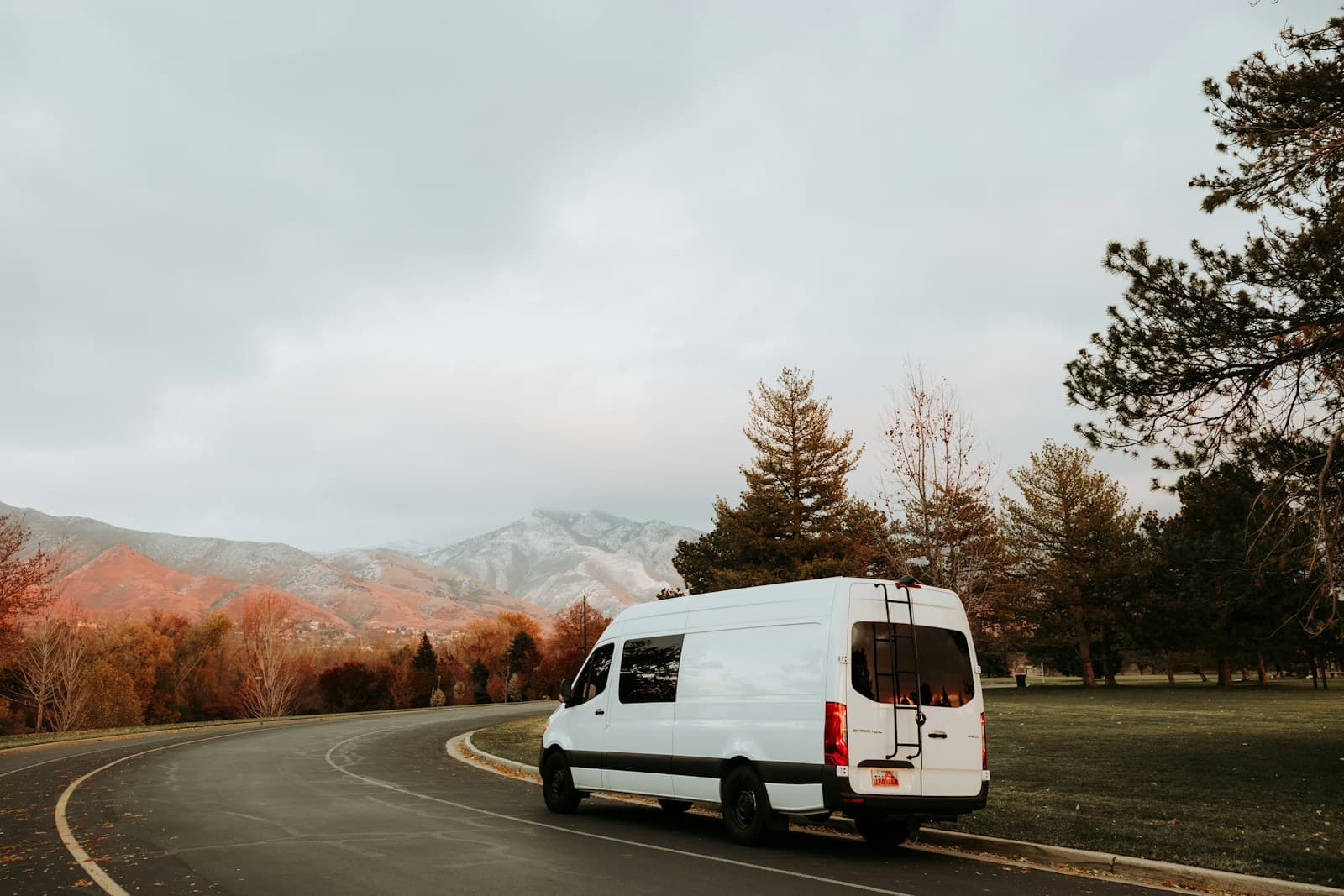 A white Sprinter van on an open road below the mountains