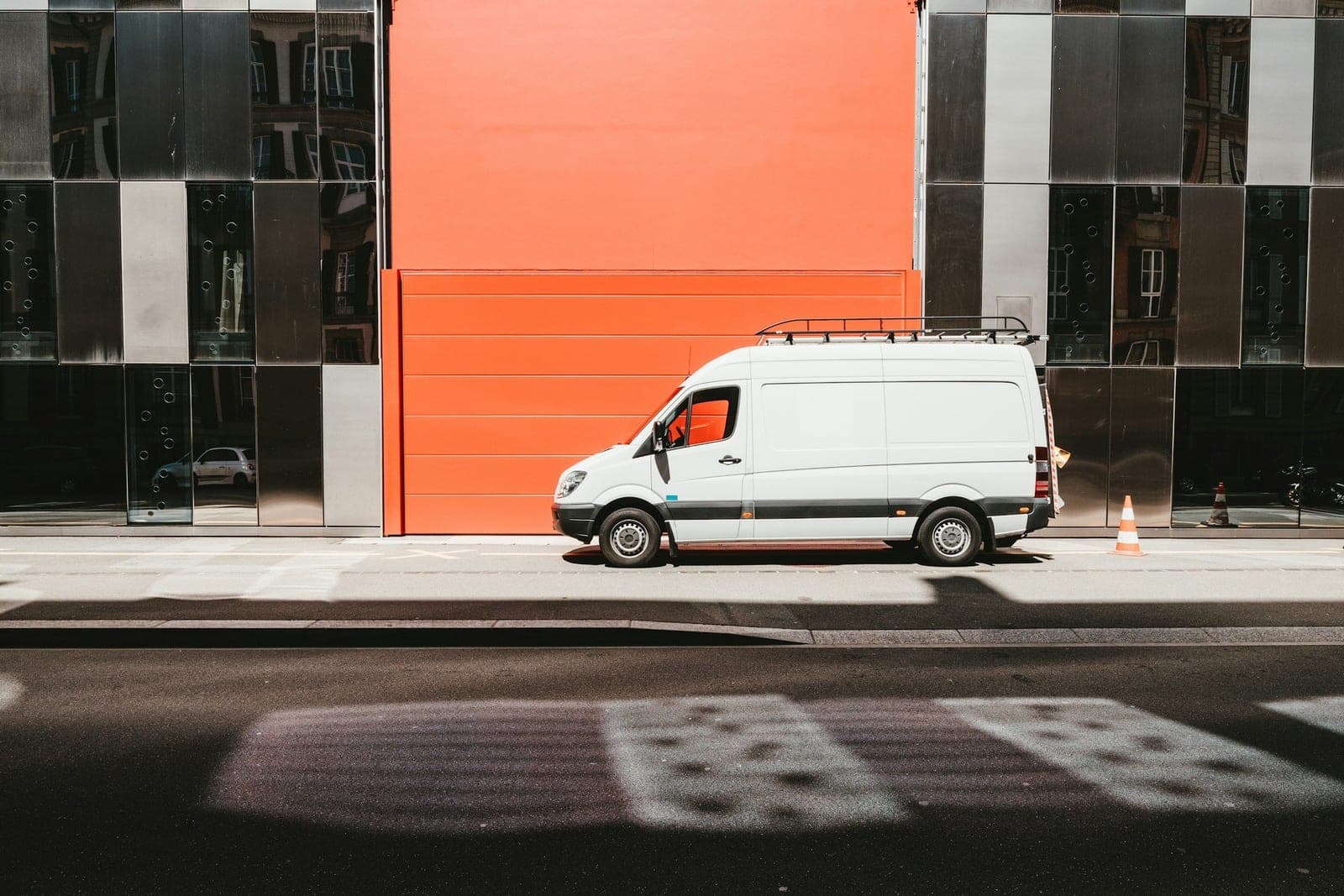 A white Sprinter van parked at a modern city building